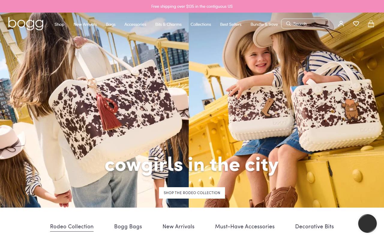 Bogg Bag官网首页截屏，顶部公告条Free shipping over $135 in the contiguous US，导航含Shop/New Arrivals/Bags/Accessories/Bits & Charms/Collections/Best Sellers/Bundle & Save，hero为Rodeo Collection cowgirls in the city母女三人黄色大桥场景