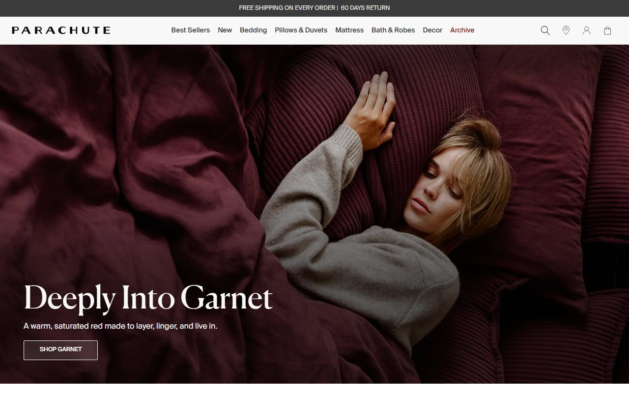 Parachute官网首页截屏，hero为Deeply Into Garnet酒红色床品生活方式实拍，导航含Best Sellers/New/Bedding/Pillows & Duvets/Mattress/Bath & Robes/Decor/Archive